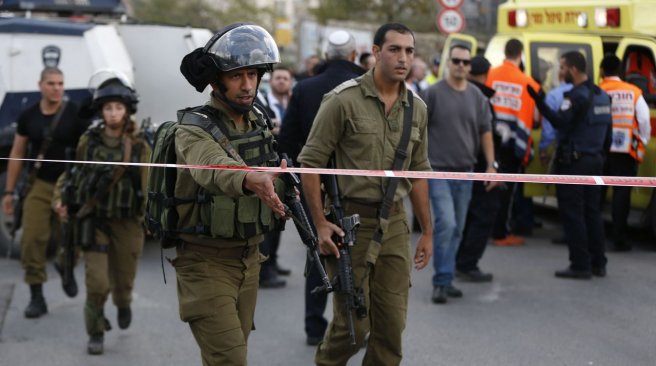 Israeli soldiers gather at the site where a Palestinian woman reportedly stabbed an Israeli security guard and was then shot by him