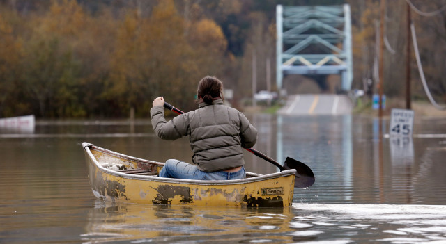 Siri Erickson Brown uses a'farm boat' an old Sears canoe with a shovel for a paddle to float across the flooded Snoqualmie River and to her home about a half-mile away Wednesday Nov. 18