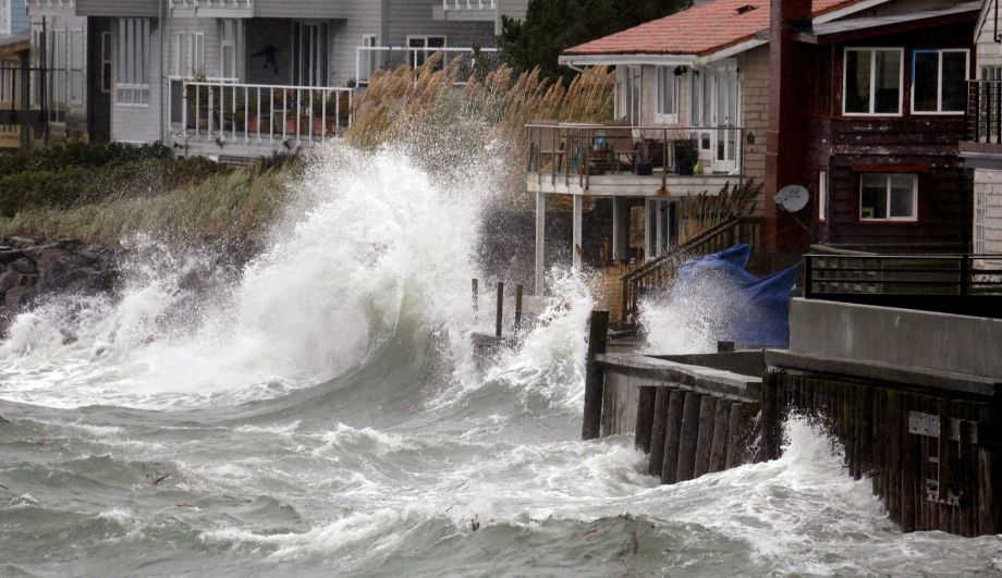 Wind-blown waves batter houses Tuesday Nov. 17 2015 in Seattle. Rain and high winds snarled the morning commute in the Puget Sound area and the Inland Northwest braced for severe weather that could include wind gusts to 70 mph. The National Weather Ser