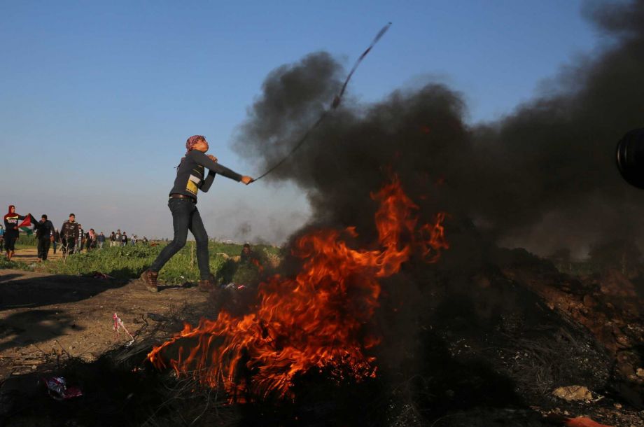 A Palestinian protester hurls stones at Israeli soldiers during clashes on the Israeli border Eastern Gaza City Friday Dec. 18 2015