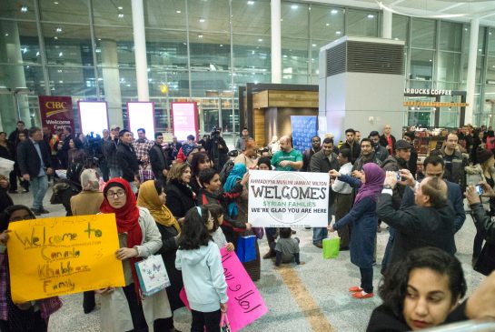 Members of groups who are sponsoring two Syrian refugee families hold up signs welcoming their charges as they wait for the families to arrive at Toronto's Pearson Airport on Wednesday Dec. 9 2015