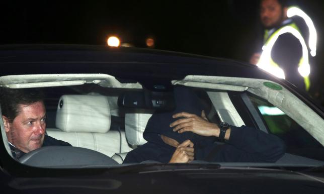 A man believed to be Jose Mourinho covers his face under a hoody as he is is driven out of Chelsea training in Cobham southern England today