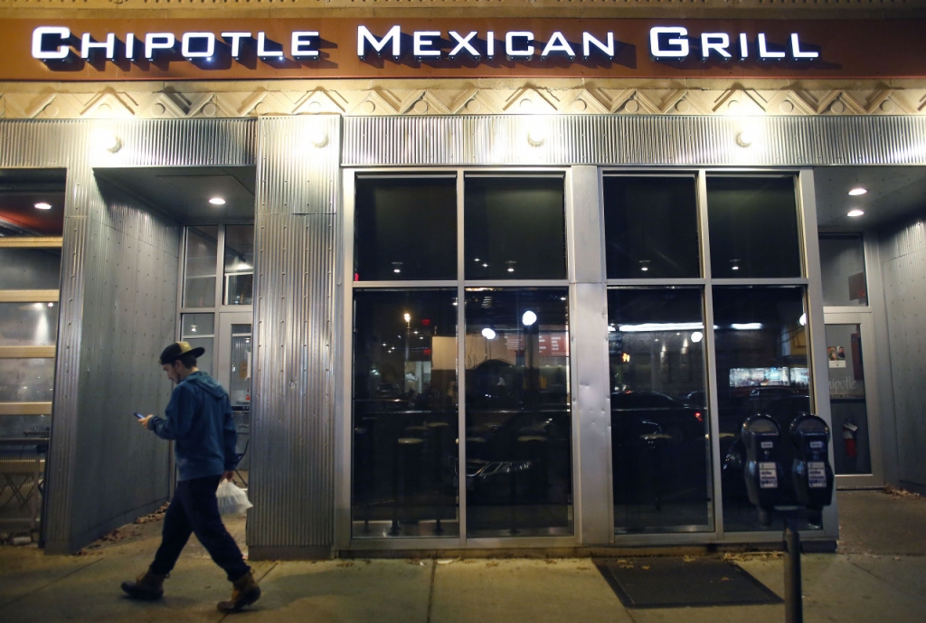 A man walks near a closed Chipotle restaurant on Monday in the Cleveland Circle neighborhood of Boston