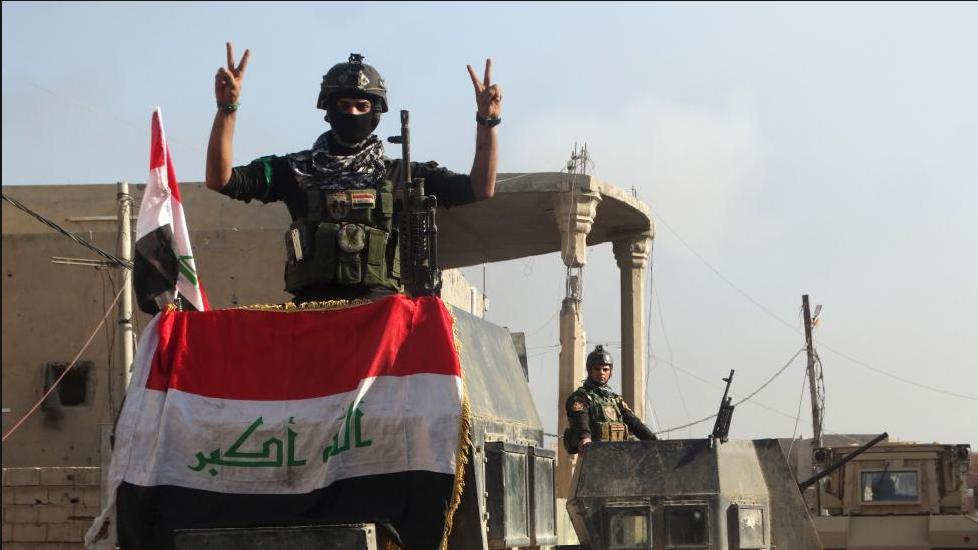 A member of the Iraqi security forces gestures at a government complex in the city of Ramadi