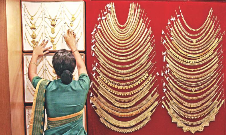 A saleswoman arranges a gold necklace inside a jewellery shop in India. Reuters  File