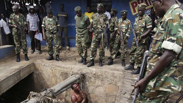 A suspected member of the Burundi ruling party's youth militia pleads with soldiers to protect him from a mob of demonstrators in Bujumbura