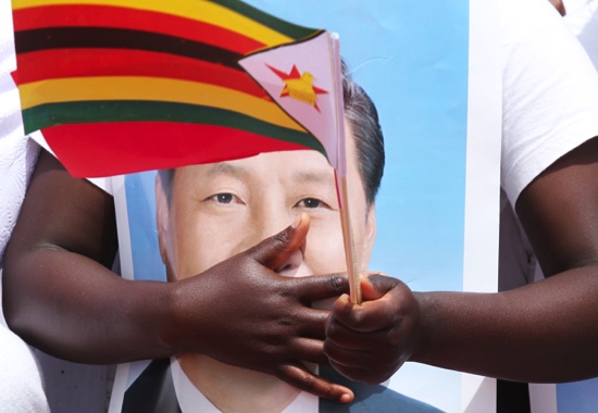 A woman holds a portrait of Chinese President Xi Jinping while welcoming him in Harare Zimbabwe