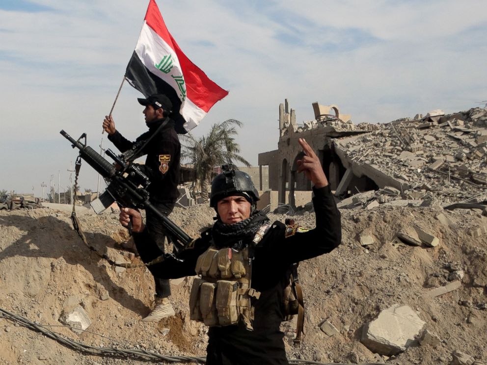 Iraqi security forces raise an Iraqi flag near the provincial council building in central Ramadi