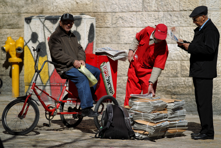 An Israel Hayom deliveryman hands out free copies to passersby in Jerusalem