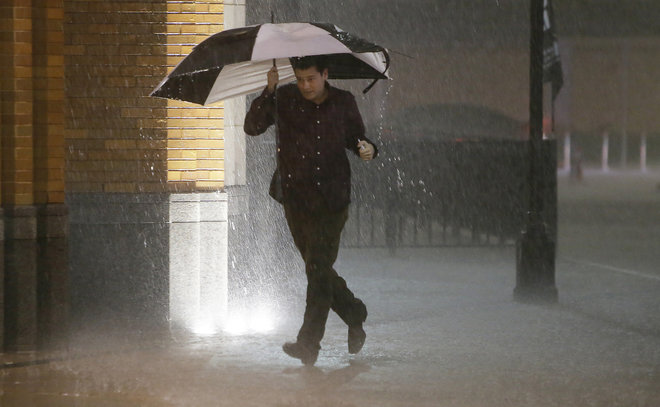 A man runs as sirens sound during a severe storm over downtown Dallas Saturday Dec. 26 2015 in Dallas. The National Weather Service said the Dallas area was under a tornado warning Saturday