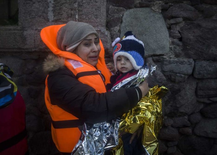 A woman holds a baby after their arrival with other refugees and migrants on a dinghy from the Turkish coast to the Greek island of Lesbos on Friday Dec. 18 2015