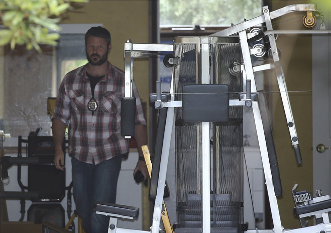 A Federal police officer walks through the garage at the home of a Sydney man in Sydney Australia Wednesday Dec. 9 2015 as they search the property as part of a tax investigation. Technology news sites have alleged the man is the creator of the virtua