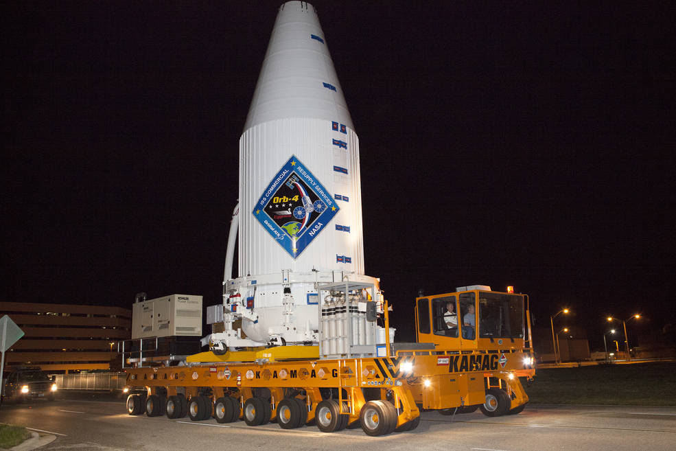 A transporter moves Orbital ATK's enhanced Cygnus spacecraft fitted inside the payload fairing of a United Launch Alliance Atlas V from the Payload Hazardous Servicing Facility at NASA's Kennedy Space Center in Florida to Space Launch Complex 41. The Cy