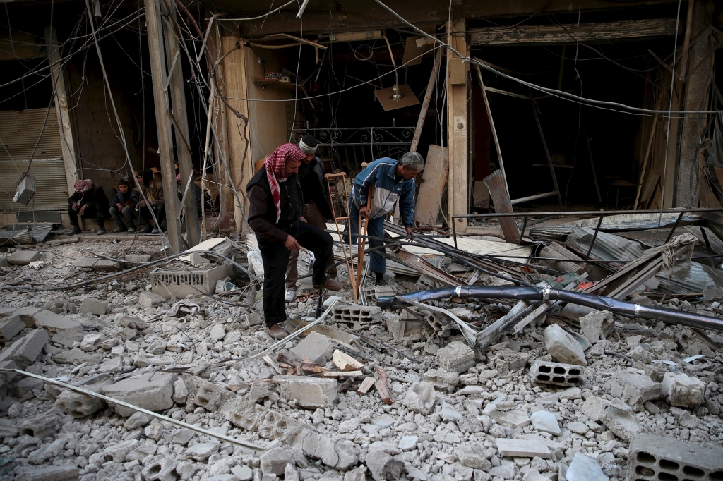 Men search for belongings at a site hit by missiles in the Douma neighborhood of Damascus