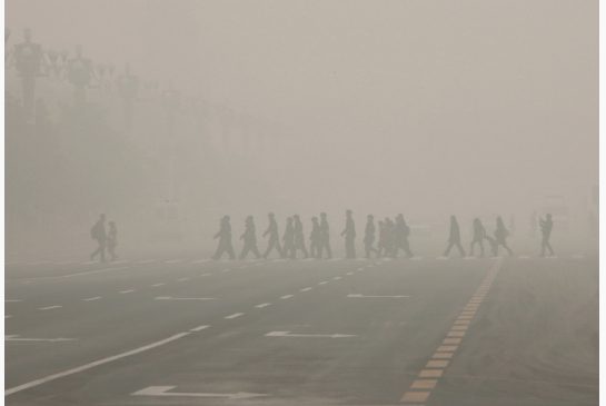 Pedestrians cross the street at a crosswalk at the Tiananmen Square on Monday. Visibility was cut to several hundred metres as buildings receded into thick smog. People complained of a smoky pungent odour and many wore tight-fitting face masks