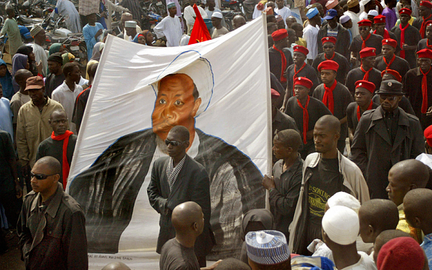 Black-shirted followers of a hardline Shiite Muslim sect carry a banner depicting Ibrahim Zakzaky