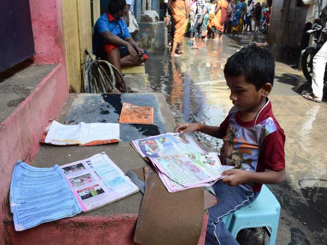 Boy puts his school books out to dry as Chennai tries to get back to normalcy. AFP