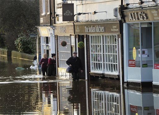 People wade through floodwater after the River Ouse bursts its banks in York city centre northern England Sunday Dec. 27 2015. Hundreds more people were told to leave their homes in northern England Sunday as Prime Minister David Cameron said more troop