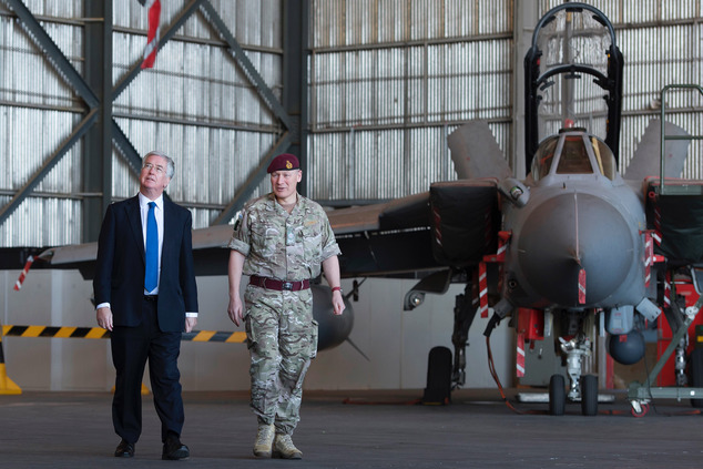 British Defence Minister Michael Fallon left walks with an unidentified officer during his visit at RAF Akrotiri a British air base near the coastal city