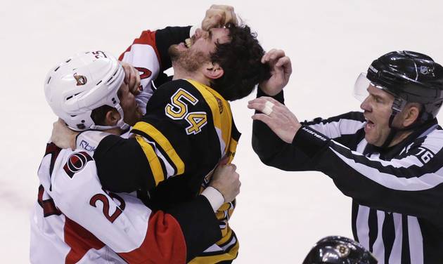 Ottawa Senators right wing Chris Neil and Boston Bruins defenseman Adam Mc Quaid gouge each other's eyes as they fight during the third period of an NHL hockey game in Boston Tuesday Dec. 29 2015. At right is referee Michael Cormier. (AP