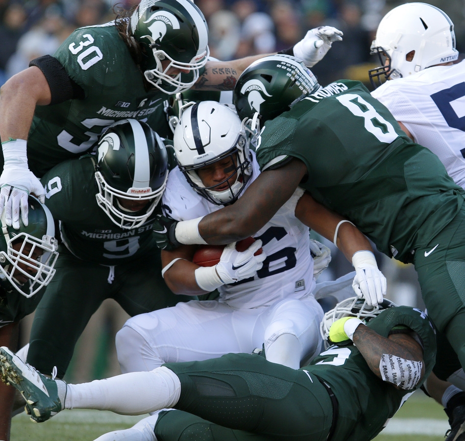 Penn State's Saquon Barkley center is tackled by Michigan State's Lawrence Thomas, Riley Bullough, Montae Nicholson and Darien Harris bottom right during the first quarter of Saturday's game in East Lansing Mich. Michigan State won 55-1