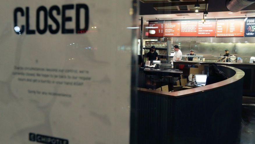 Dec. 7 2015 People stand inside a closed Chipotle restaurant in the Cleveland Circle neighborhood of Boston. Chipotle said late Monday that it closed the restaurant after several students at Boston College including members of the men'�s basketb