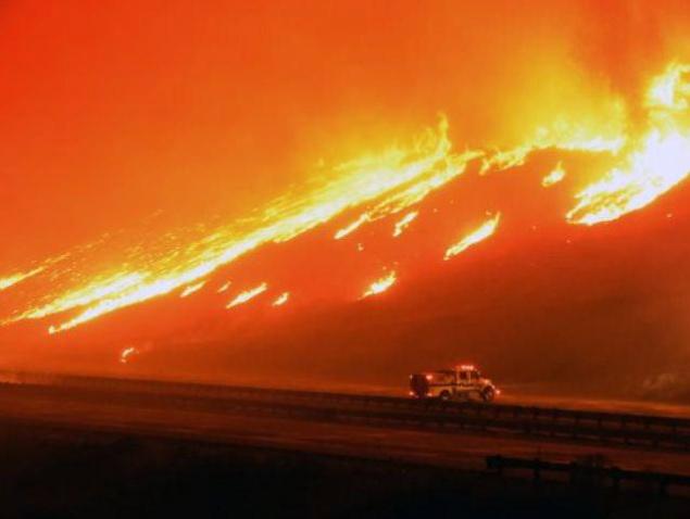 A Ventura County Fire Department engine holds its positions as fire overruns state Highway 101 near Ventura California on Saturday. A wind-whipped wildfire in Southern California burned over 1,000 acres of land forced the closure of parts of two major