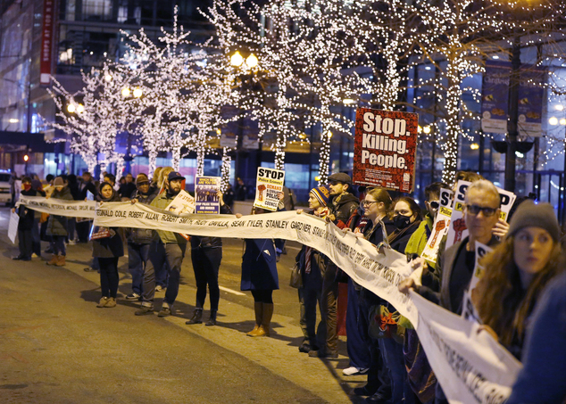 Protesters march through Chicago's Loop carrying what organizers say is a banner of names of people tortured and in prison as they also call for Chicago May