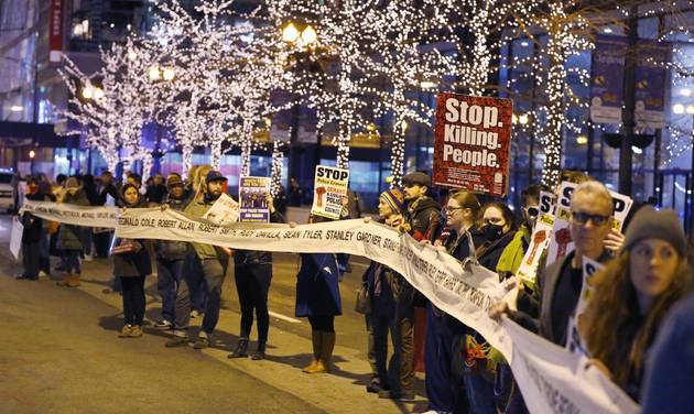 Protesters march through Chicago's Loop carrying what organizers say is a banner of names of people tortured and in prison as they also call for Chicago Mayor Rahm Emanuel and Cook County State's Attorney Anita Alvarez to resign in the wake