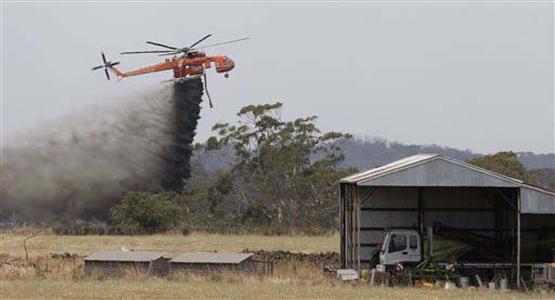 Skycrane helicopter drops a load of water as it works to hold back a wildfire from the hamlet of Claredon in Victoria Australia. More than 100 homes have been destroyed by the Christmas Day wildfire that tore throug