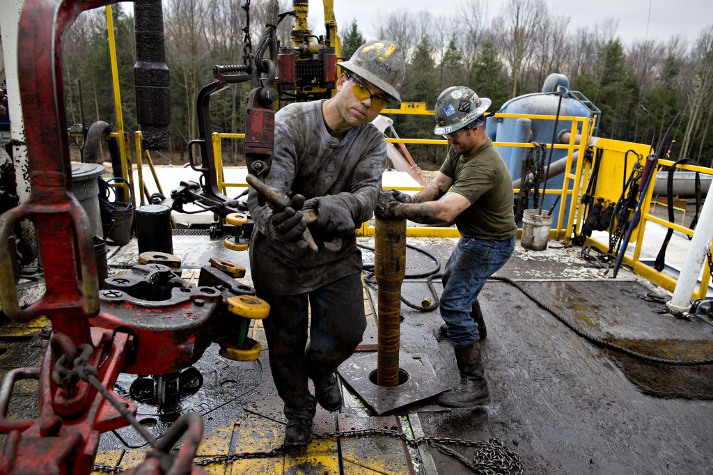 Nomac Drilling Corp. floorman Matthew Brown right prepares the drill string for an additional length of drill pipe as as floorman Richard Lane moves a piece of equipment during natural gas drilling operations for Chesapeake Energy Corp. in Bradford Coun