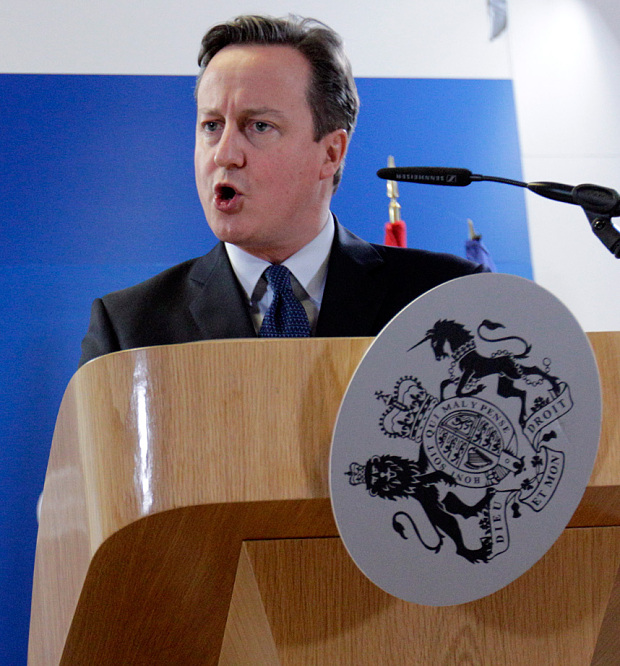 David Cameron speaks during a media conference at an EU summit as the British coate of arms hangs from the dispatch box