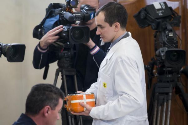 An assistant carries the flight data recorder from