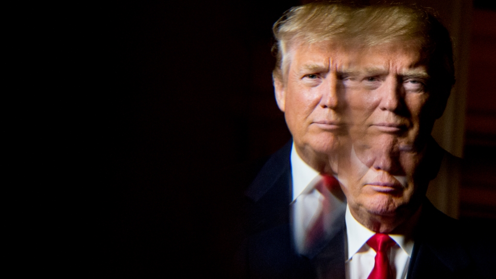 Donald Trump seen in a reflection while posing for a portrait following an interview with The Associated Press