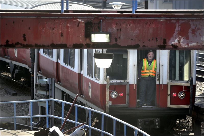 A worker stands at an entrance to a passenger train as it rests on tracks today in Boston. The six-car train with passengers on board left a suburban Boston transit station without a driver Thursday and went through four stations without stopping was tam