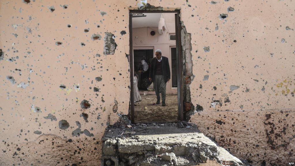 FILE- People walk inside their damaged house in the Sur district in Diyarbakir Turkey Dec. 11 2015