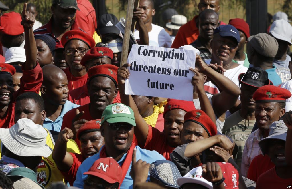 FILE- Protesters hold a placard demanding an end to corruption at a rally in Pretoria South Africa Sept. 30 2015