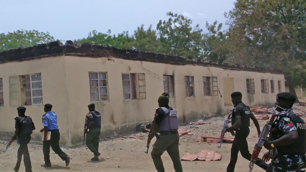 FILE- Security guards walk past a burned-out government secondary school in Chibok Nigeria in April 2014