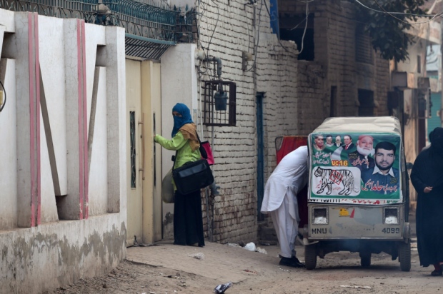 A woman and elderly man leave the house of Gulzar Ahmed Malik