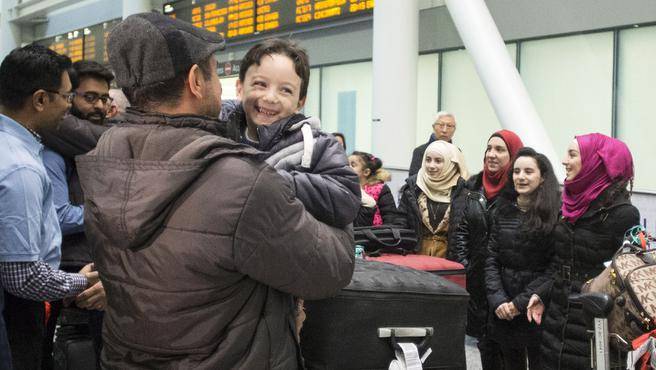 Six-year-old Ahmad Mazan Khabbaz a refugee from Syria smiles as he is greeted by family friend Rakan Almasri himself a recent arrival to Canada from Syria as the youngest member of his family arrives with his parents and sisters at Toronto's Pear