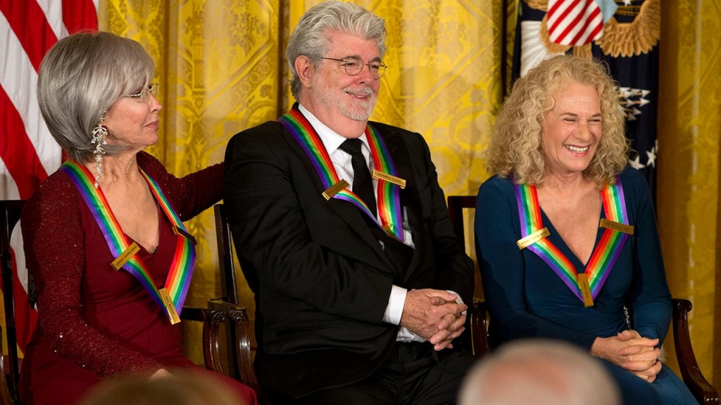 2015 Kennedy Center Honors honorees from left actress and singer Rita Moreno filmmaker George Lucas and singer-songwriter Carole King react as President Barack Obama speaks