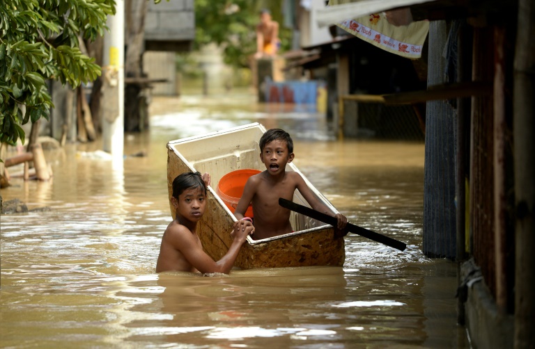 AFP  Noel Celis Children use a refrigerator as a boat to cross a flooded alley in Candaba Pampanga north of Manila