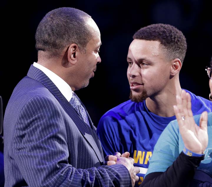 Former Charlotte Hornets player Dell Curry is congratulated by son Stephen Curry after being honored at halftime