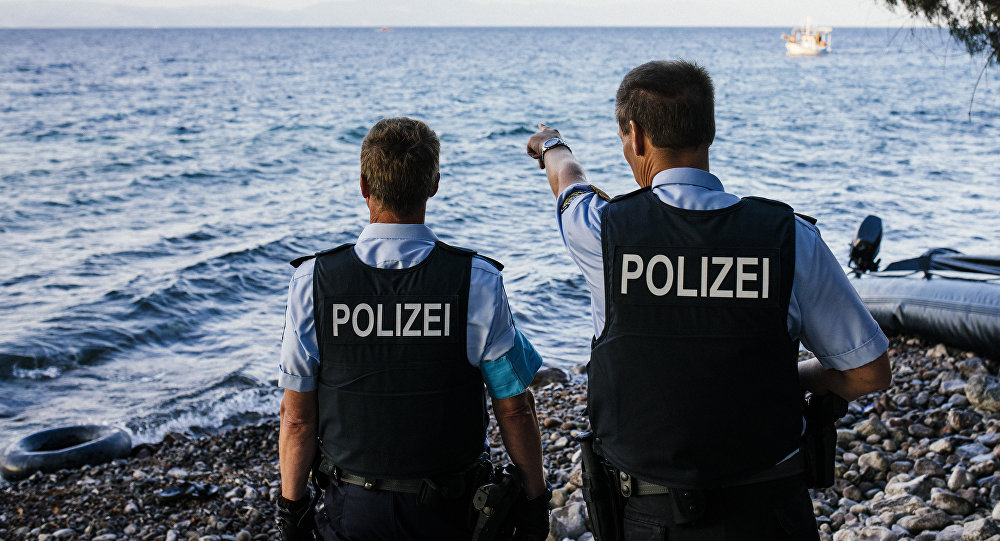 German police officers representatives of the EU's border management agency Frontex on the Greek island of Lesbos look at a dinghy with migrants crossing the Aegean sea from Turkey