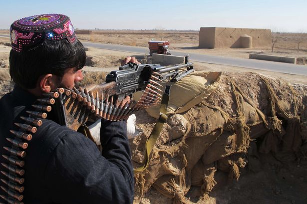 An Afghan Local Police personnel keeps watch during an ongoing battle with Taliban militants