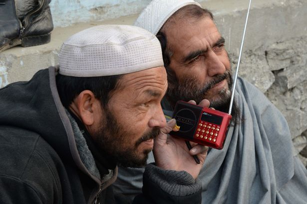 Afghan men listen to a radio broadcast run by the Islamic State group in Jalalabad