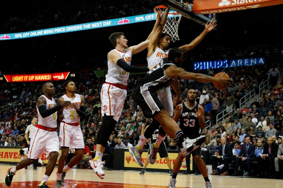 San Antonio Spurs forward Kawhi Leonard passes to center Boris Diaw while being defended by Atlanta Hawks forward Mike Muscala and guard Thabo Sefolosha as forward Paul Millsap and forward Kent Bazemore look on in the first hal