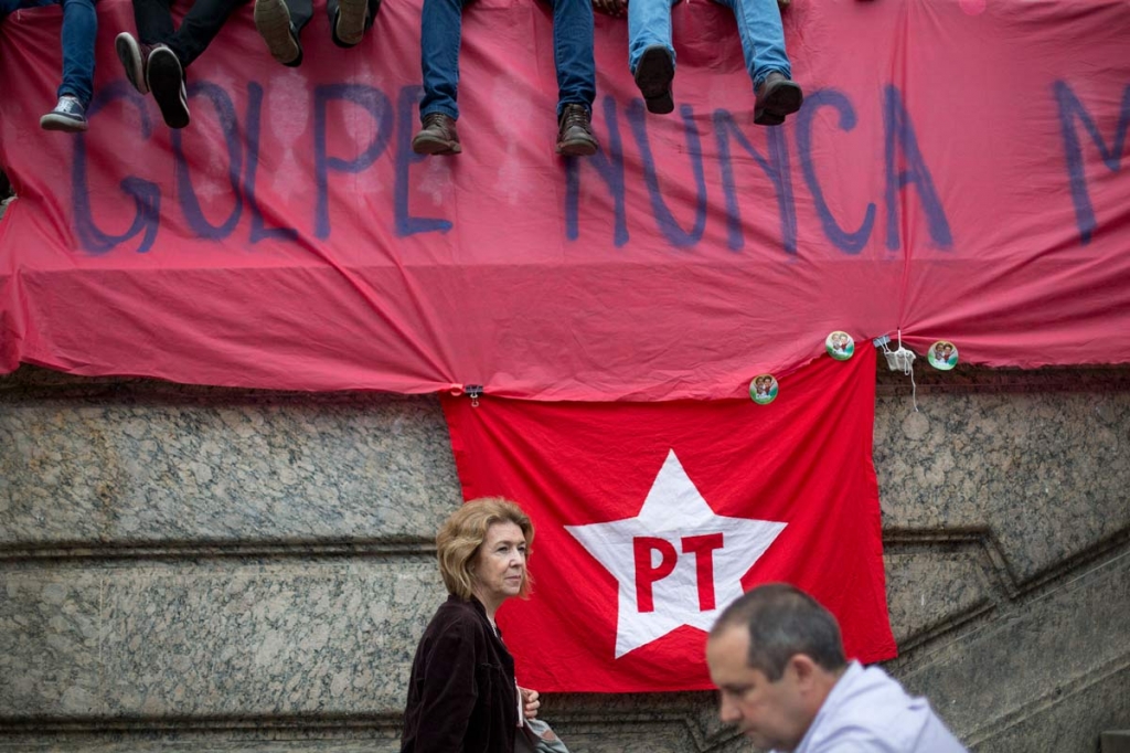 People walk next to a banner that reads'Coup Never Again during a protest against the impeachment proceedings against Brazil's President Dilma Rousseff in Rio de Janeiro Brazil Tuesday Dec. 8 2015