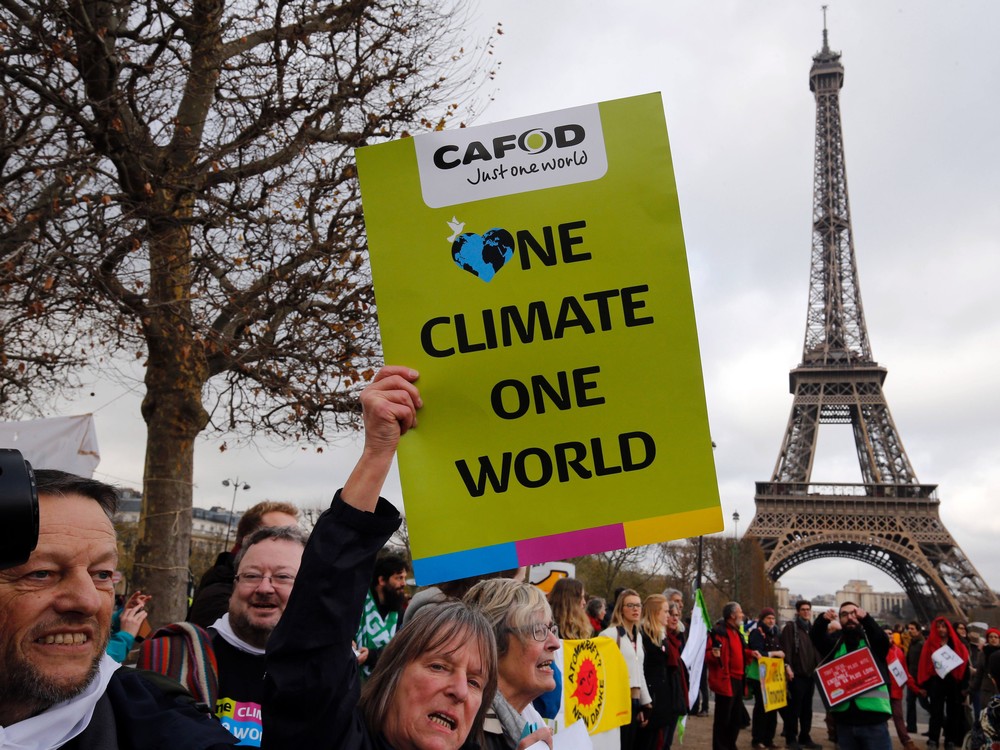 A demonstrator holds a banner reading'One climate one world during a rally held by several Non Governmental Organisations  to form a human chain on the Champs de Mars near the Eiffel Tower in Paris