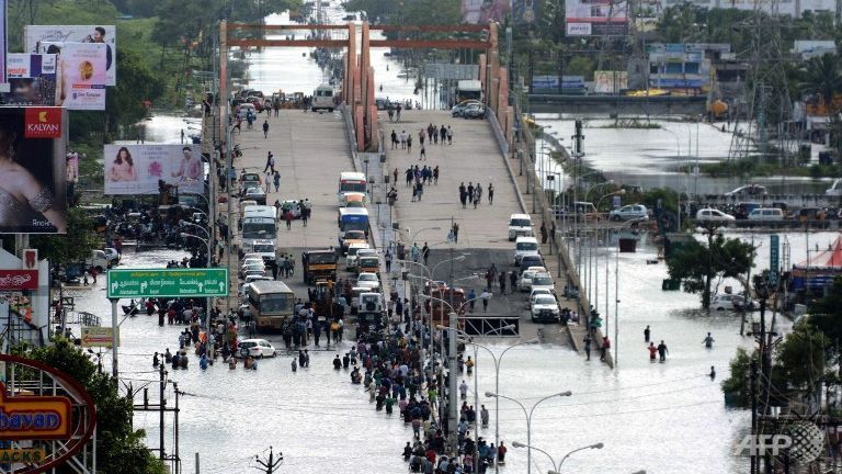 Indian residents and motorists gather on a flyover as others wade through floodwaters in Chennai
